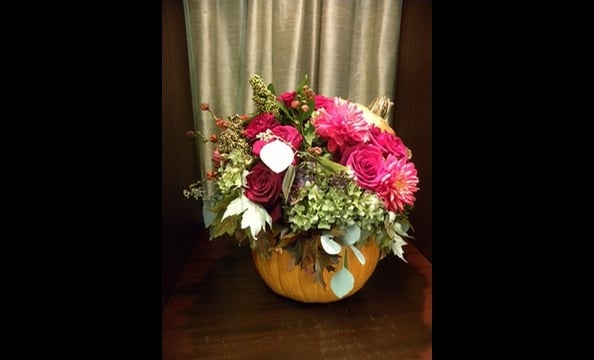 Hydrangeas, black magic roses, dahlias, amaranthus, oak leaves, and seeded eucalyptus arranged in a pumpkin.