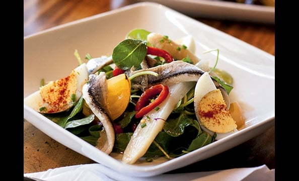 Traditional Spanish ingredients such as boquerones and roasted peppers accent an arugula salad at Estadio.