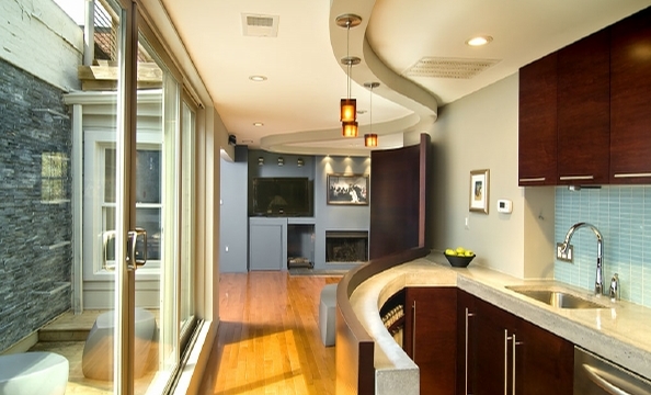 A curved bar provides storage in this narrow Capitol Hill kitchen, just six feet across at its widest point. Floor-to-ceiling windows, which overlook the deck, make the space feel bigger.