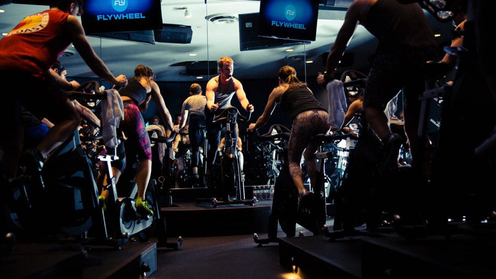 DC gyms fitness-tracking. Flywheel classes are set up stadium-style with screens at the front, which display riders' Torqboard statistics. Image courtesy of Flywheel Sports.