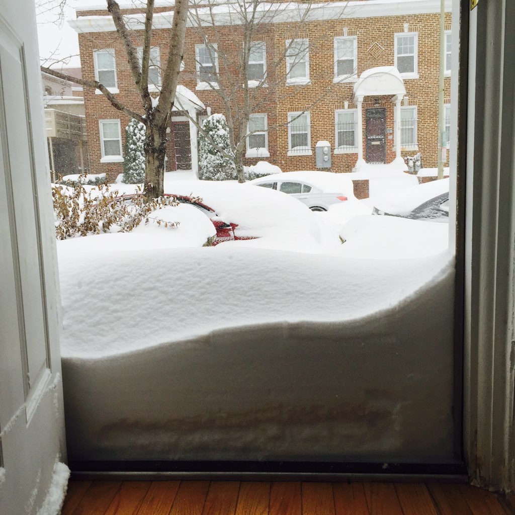 Snow pilled up outside of a person's door, visible right after they open it. 