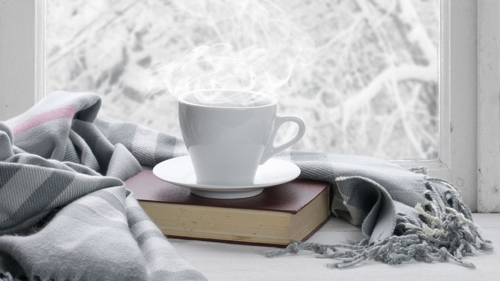 Cup of coffee on a book by the window.