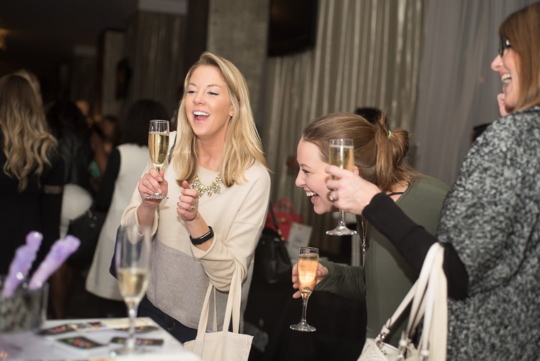 Guests laugh over champagne at the showcase. 