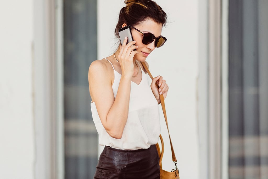 Business woman with mobile phone and bag on shoulder.