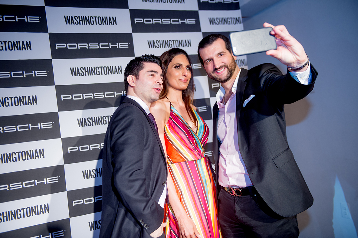 Guests pose for a selfie in front of the Porsche and Washingtonian step and repeat. 