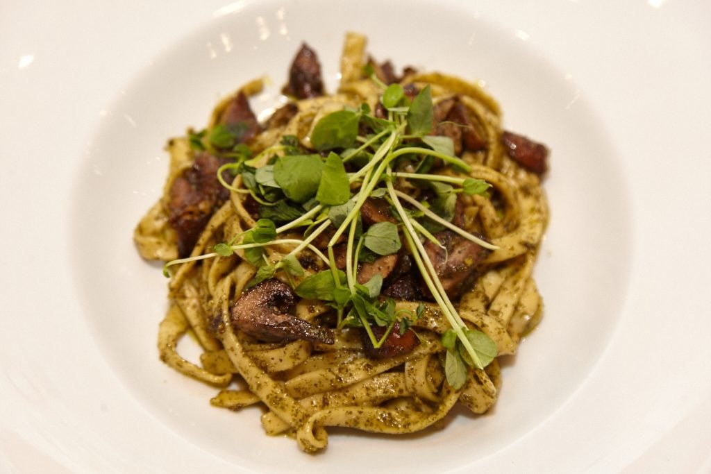 The menu emphasizes house-made items, including breads, seitan, nut-based cheeses, and pastas like this mushroom scampi.