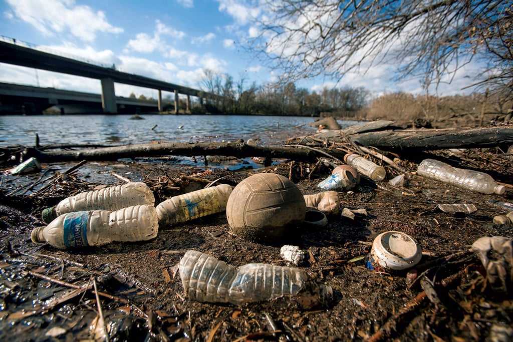 Plastic bottles and other debris float on the banks of the river. Photograph by EPA/Alamy.