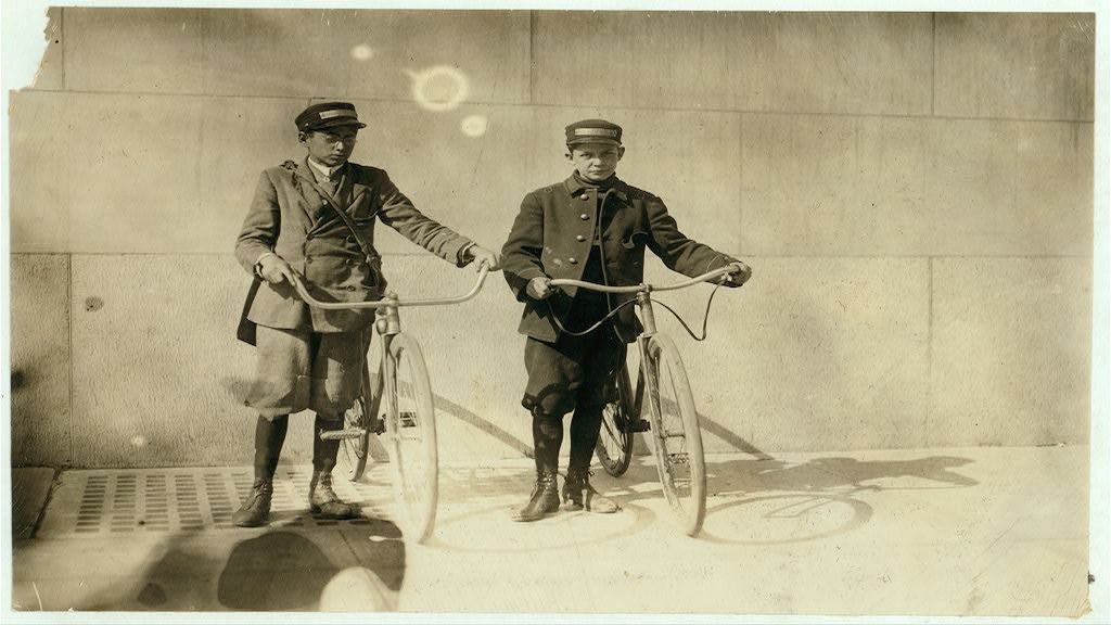 Bike messenger boys Earle Griffith and Eddie Tahoory working April of 1912. Photograph by Lewis Wickes Hine \ via Library of Congress