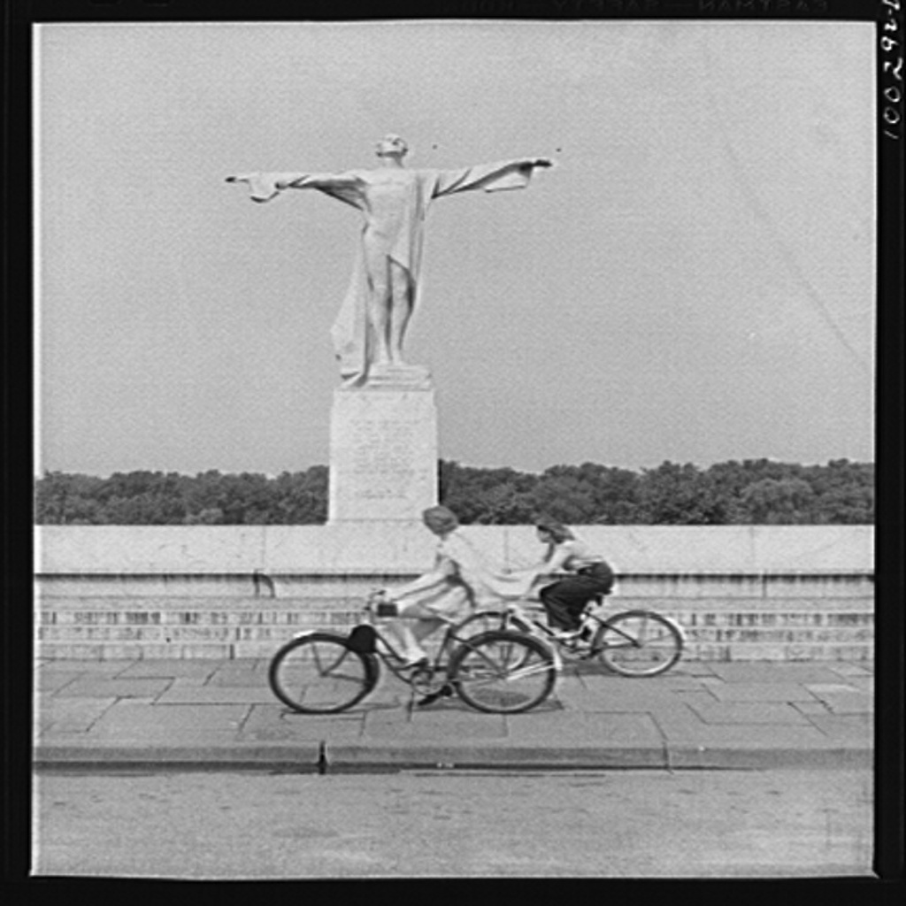 Bikers pass a statue in East Potomac Park erected in memory of the victims of the Titanic. Photograph by Marjory Collins