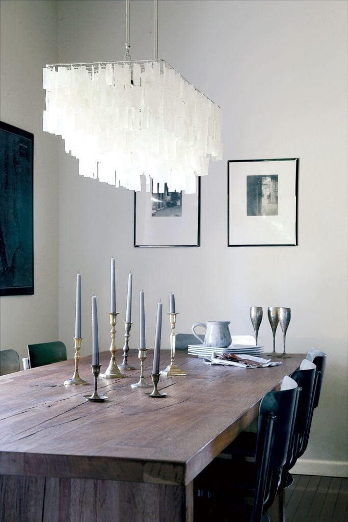 A wooden table adds rusticity. The Capiz-shell chandelier is from West Elm, the metal chairs from Restoration Hardware. Photo by Christopher Shane.