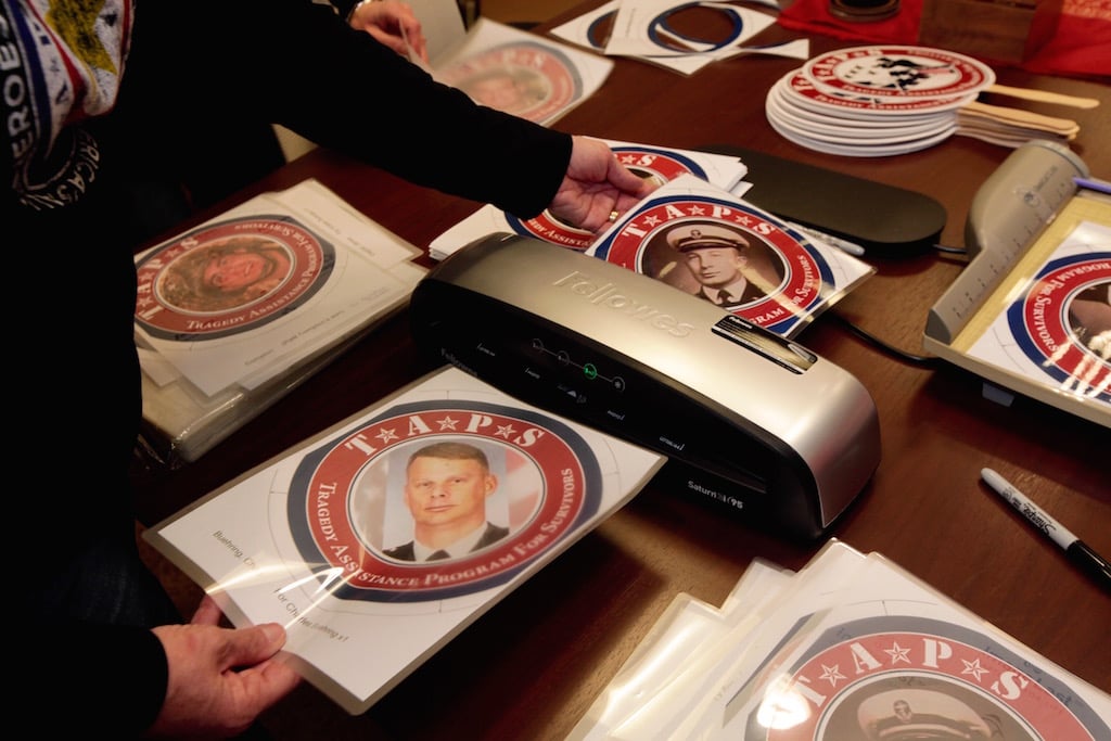 Volunteers laminate photos before super gluing them to fans to be held in the parade.