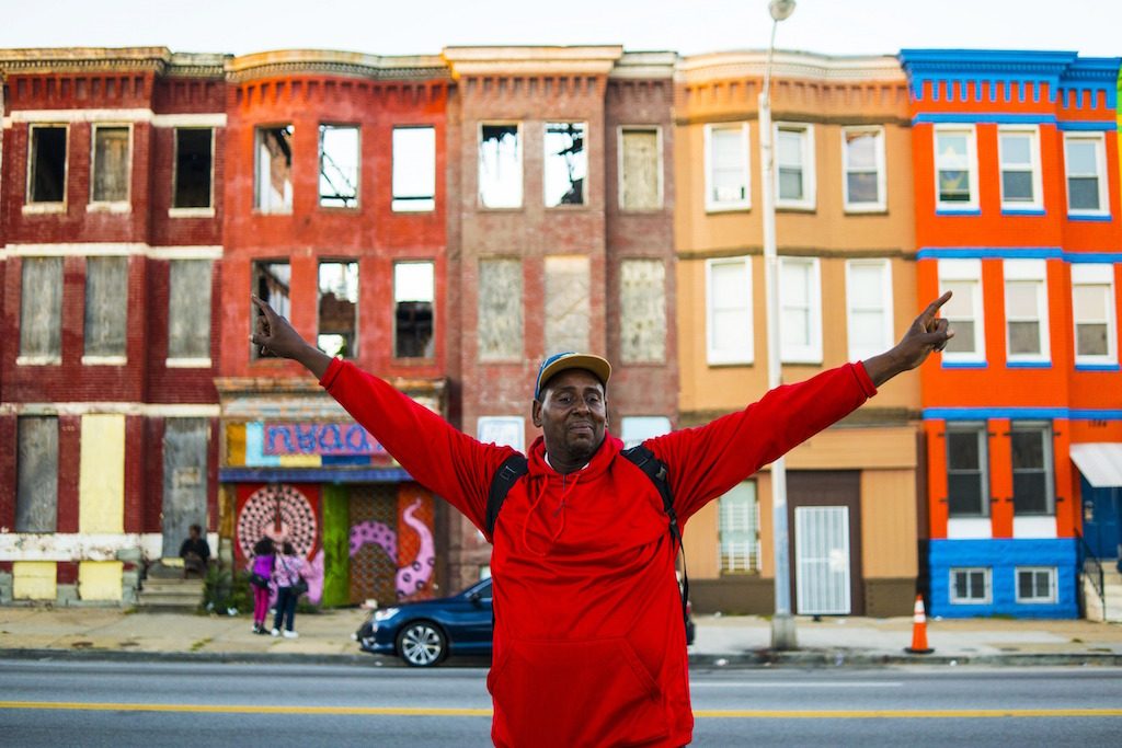 Photograph by Devin Allen of a man standing in front of colorful row houses - Washingtonian