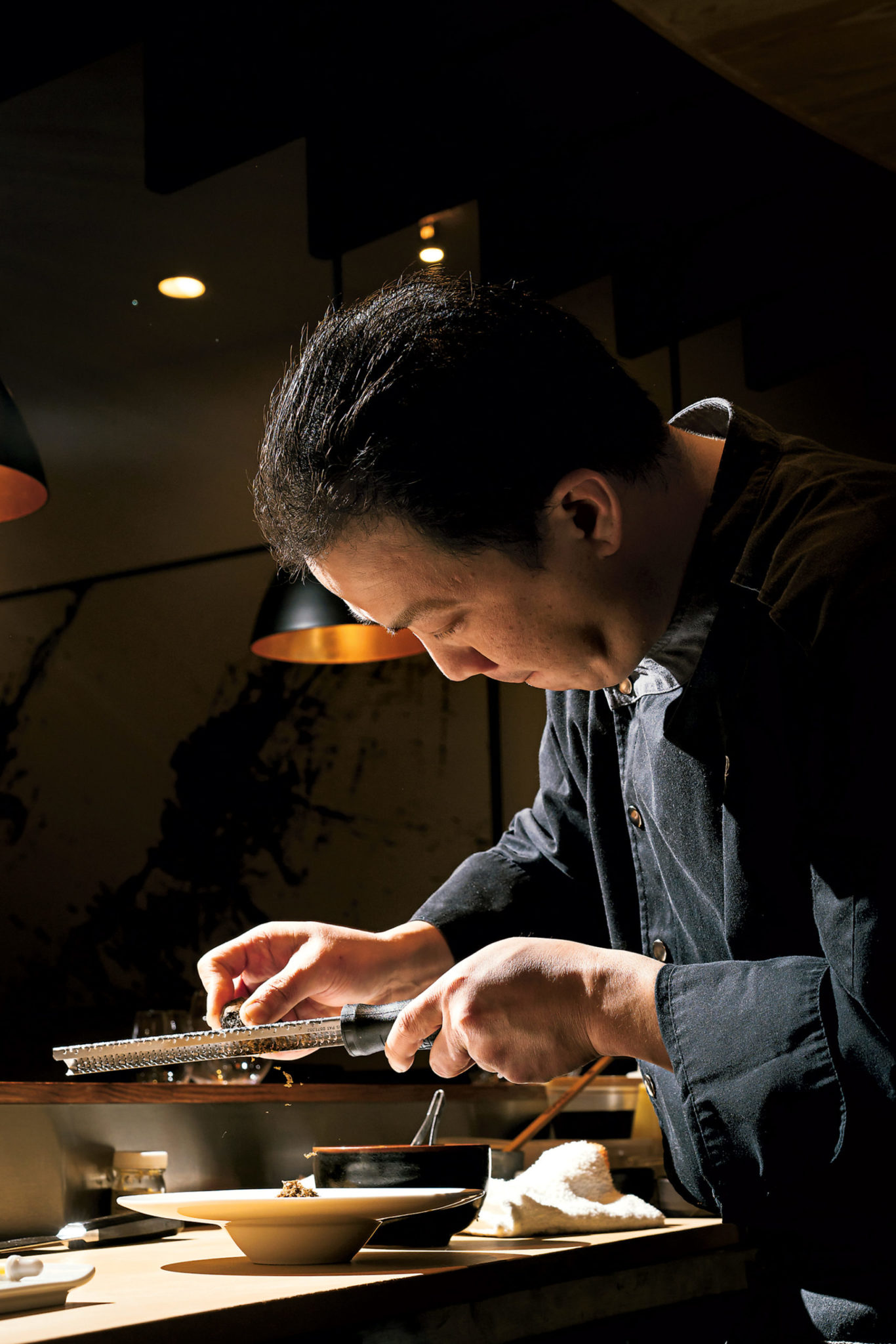 Piter shaves truffle over a risotto-like congee, slow-cooked for hours with dashi. Photograph by Scott Suchman.