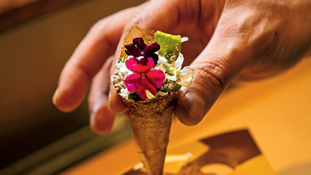 It takes a day to make delicate cones of potato starch, soy, and yuzu, which are used instead of nori for hand rolls stuffed with baby lettuce, orange powder, and edible flowers. Photograph by Scott Suchman.