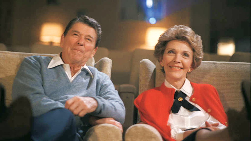 Ronald and Nancy Reagan watch a movie in the White House theatre.