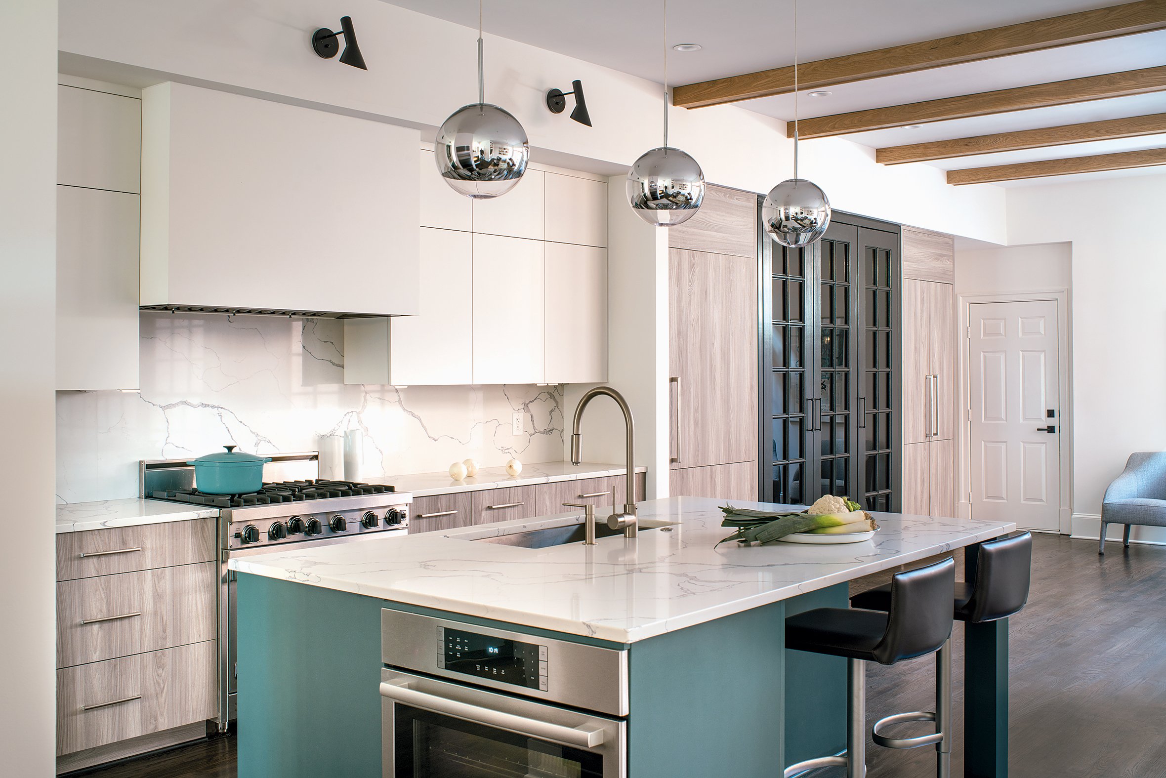 With the different light fixtures and cabinet colors, designer Sarah Kahn Turner unified the space via a single material for countertops and backsplash. Photograph by John Cole Photo.