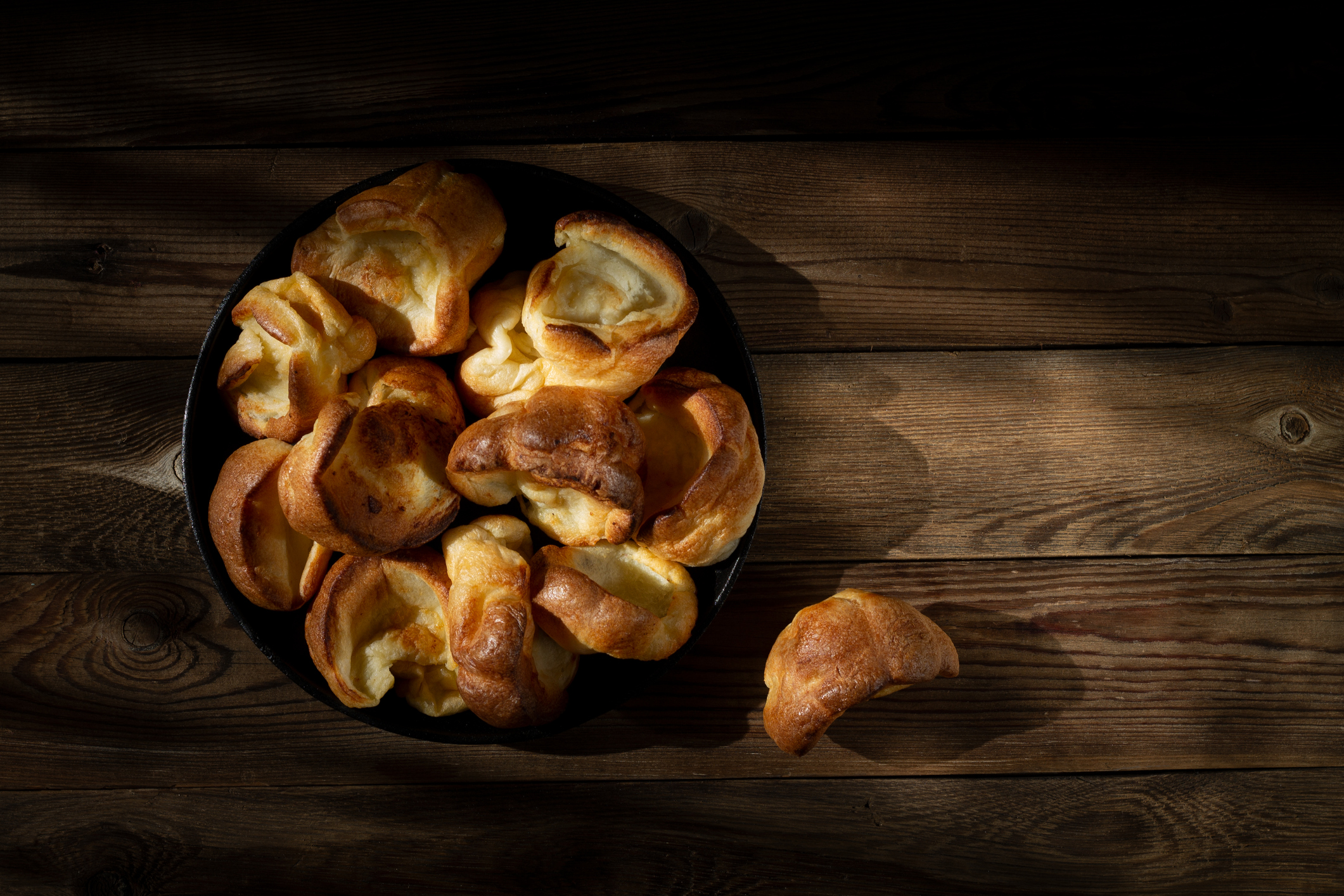 Yorkshire puddings in a cast-iron frying pan on a wooden table. Rustic style - Washingtonian