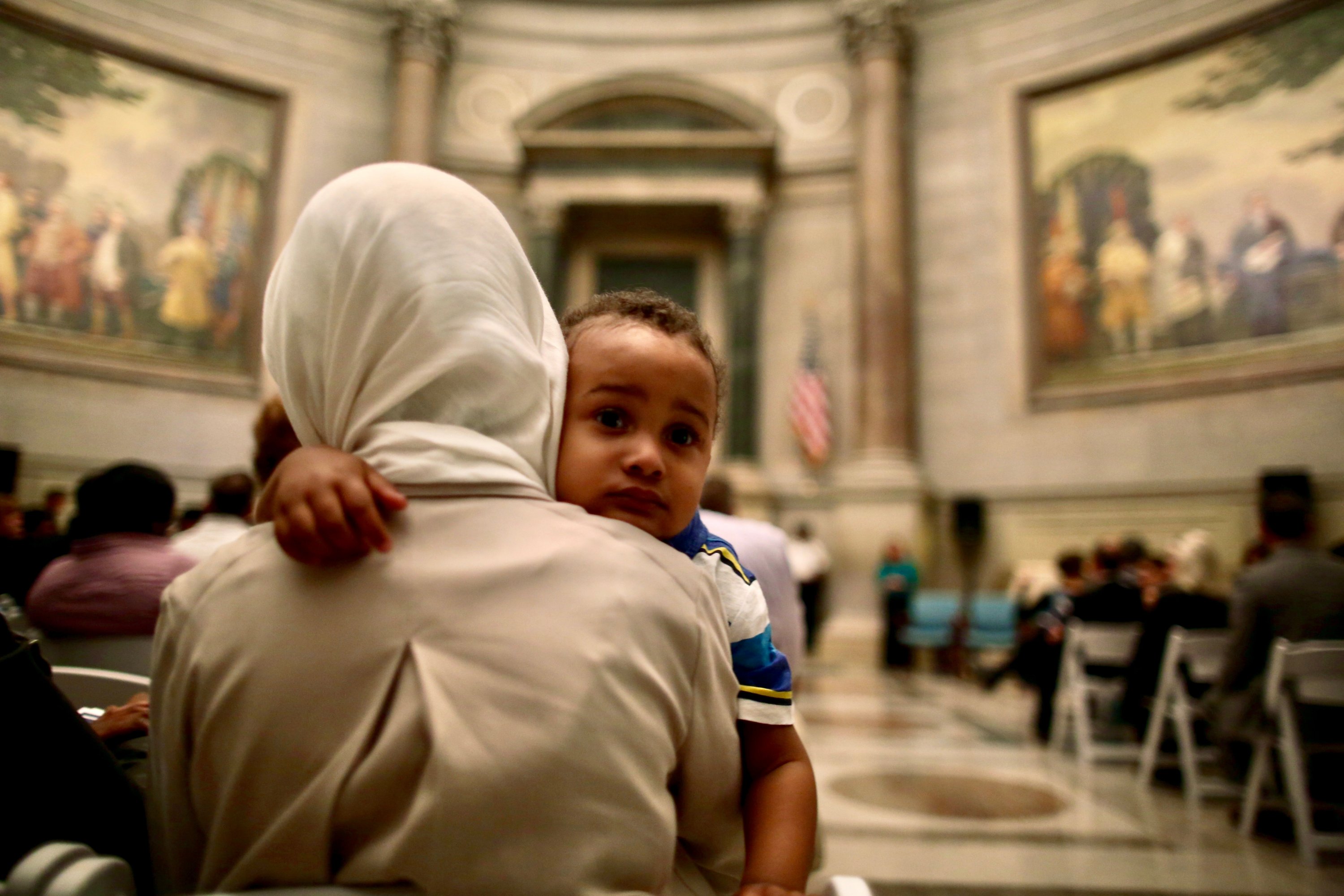 Photographs of Immigrants Becoming U.S. Citizens: A mother holds her child while attending a naturalization service at the National Archives.