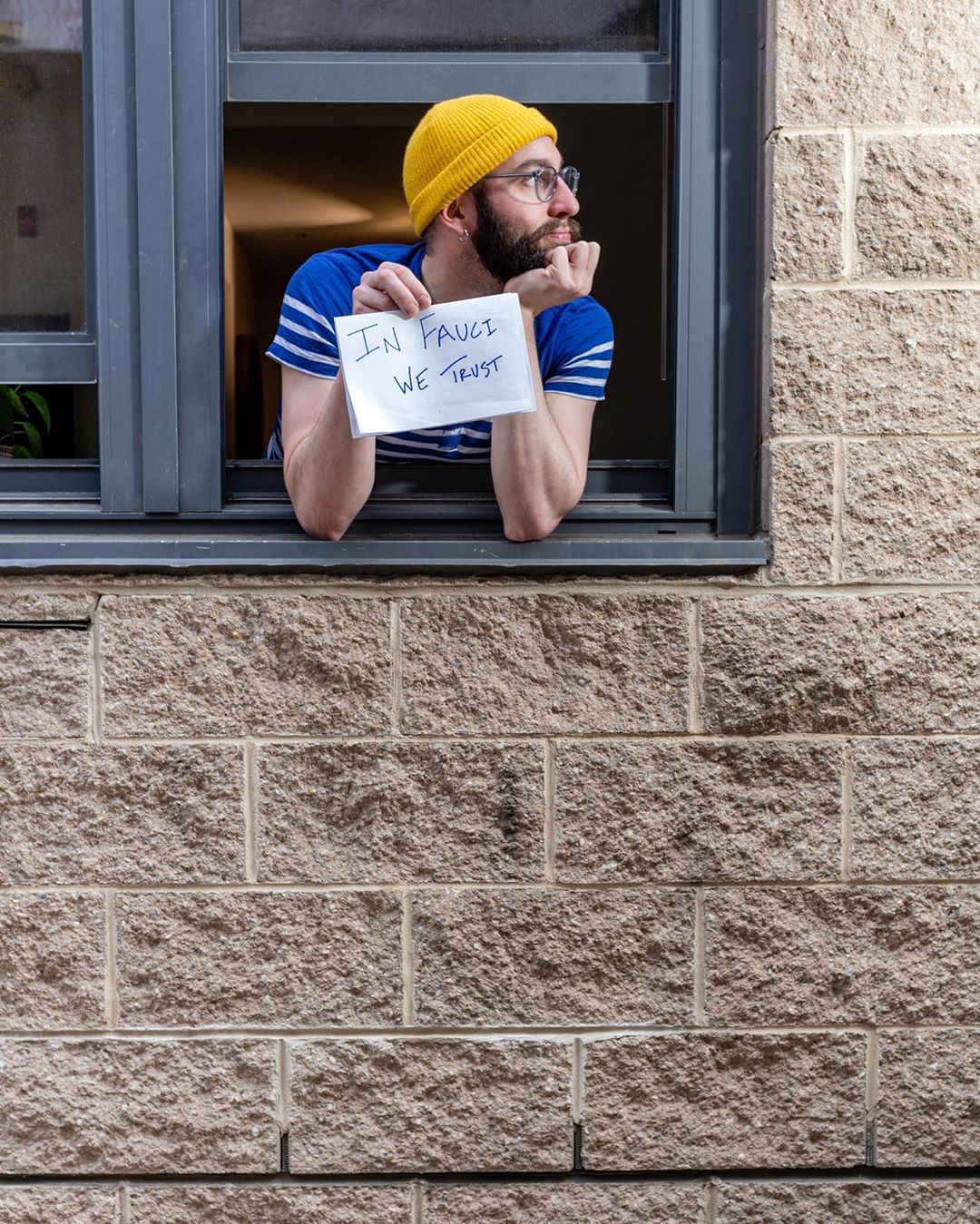 Leaning out of a window with a sign: "In Fauci We Trust." Photo courtesy of DC Public Library. 