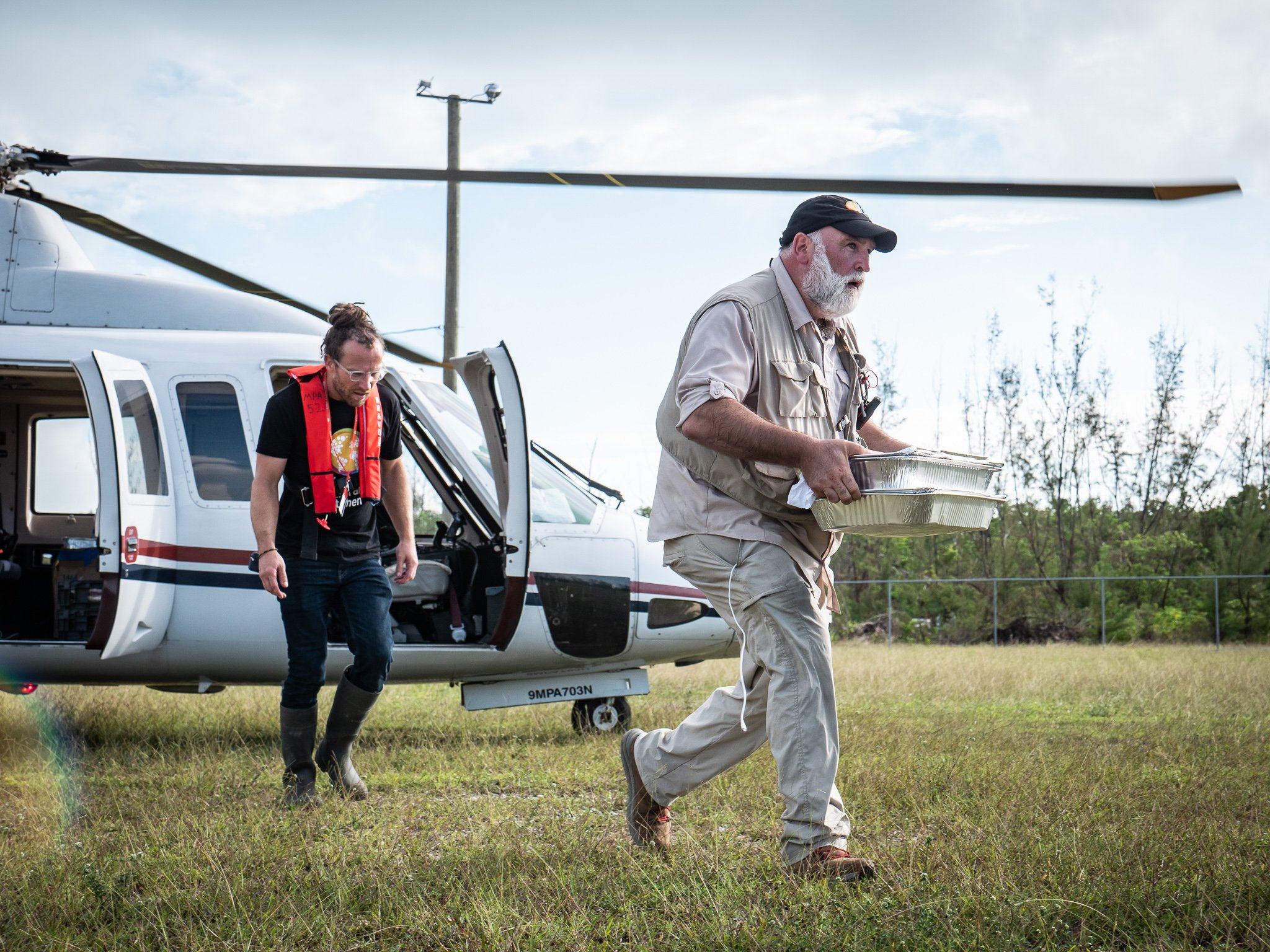 The chef with a hot meal and a helicopter in the Bahamas. Photo courtesy of World Central Kitchen.