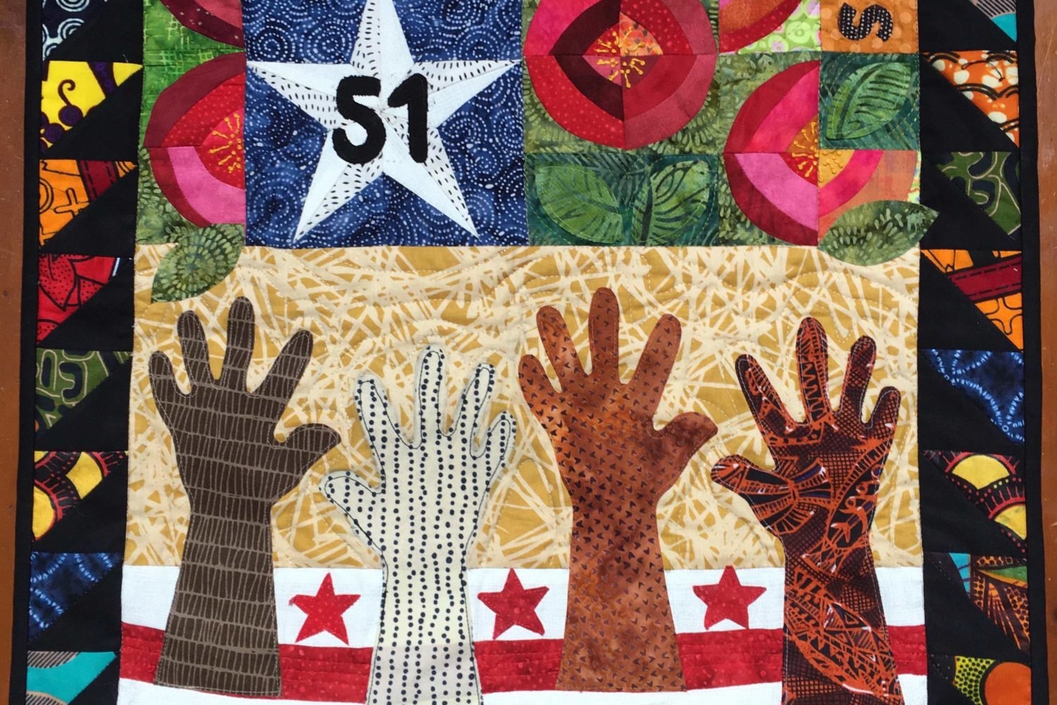 A variety of hands reach up towards the 51st star, symbolizing the public desire for DC statehood.