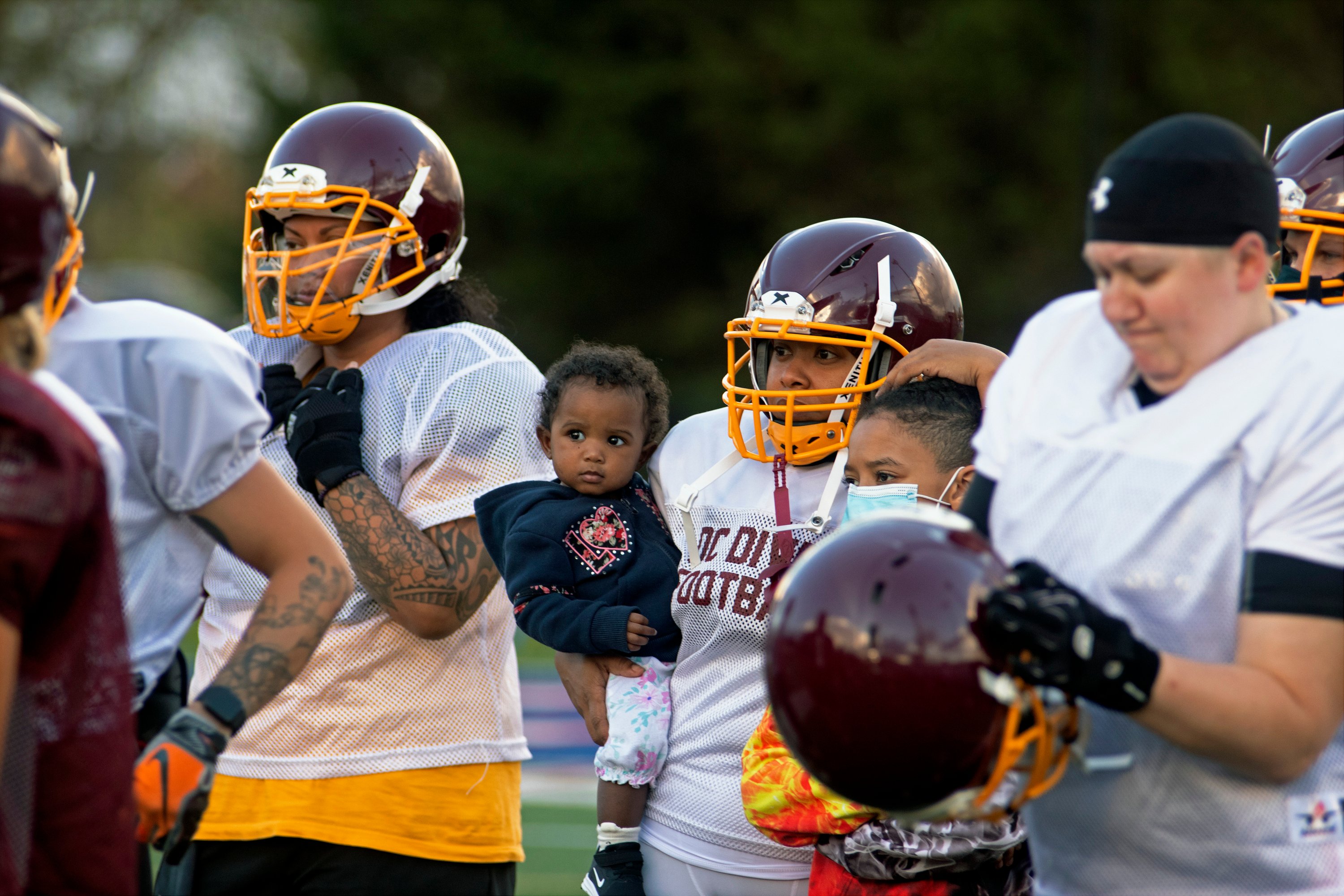 D.C. Diva football player Christina Burton stands on the sidelines with her daughter and son