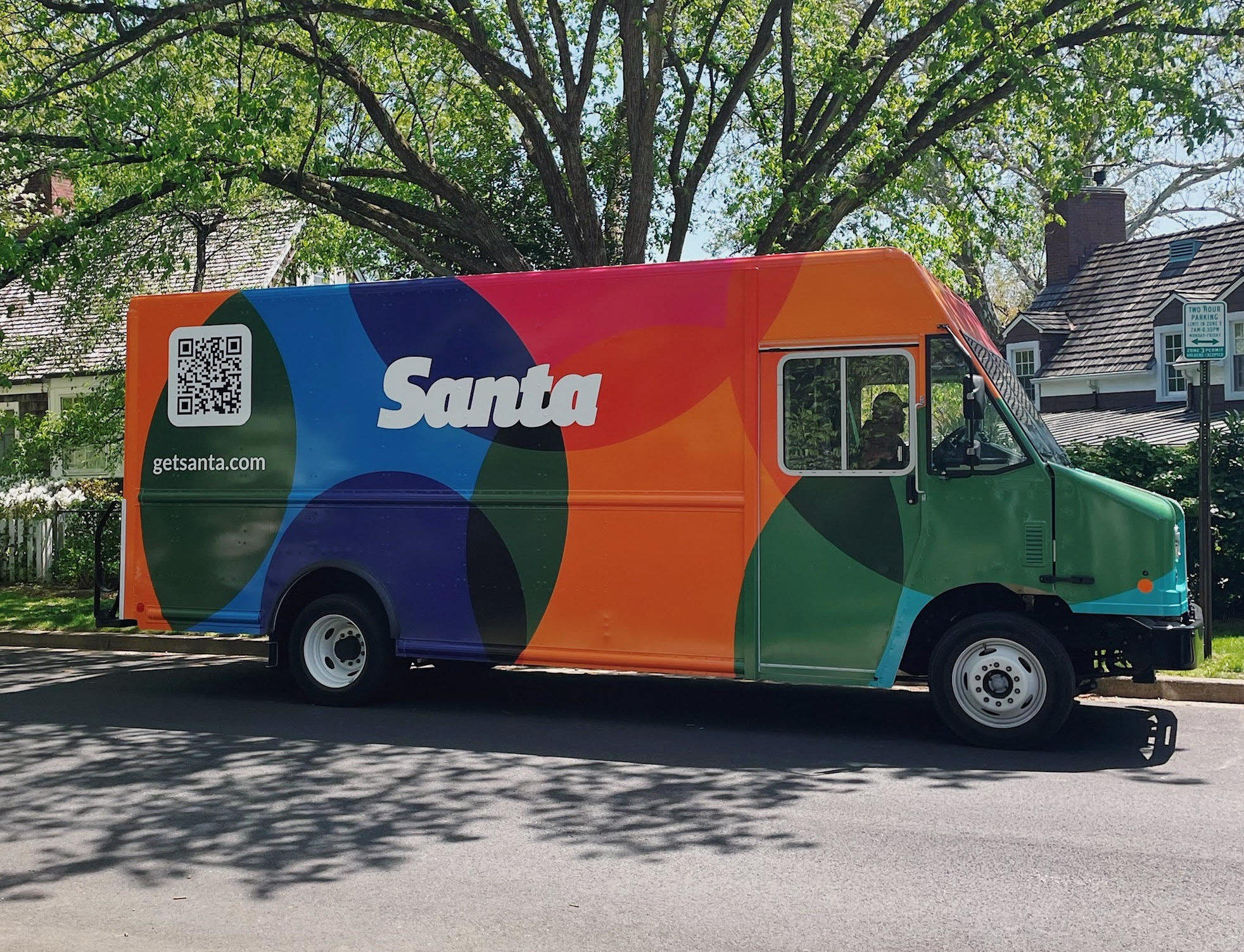 A giant, colorful truck in front of a tree.