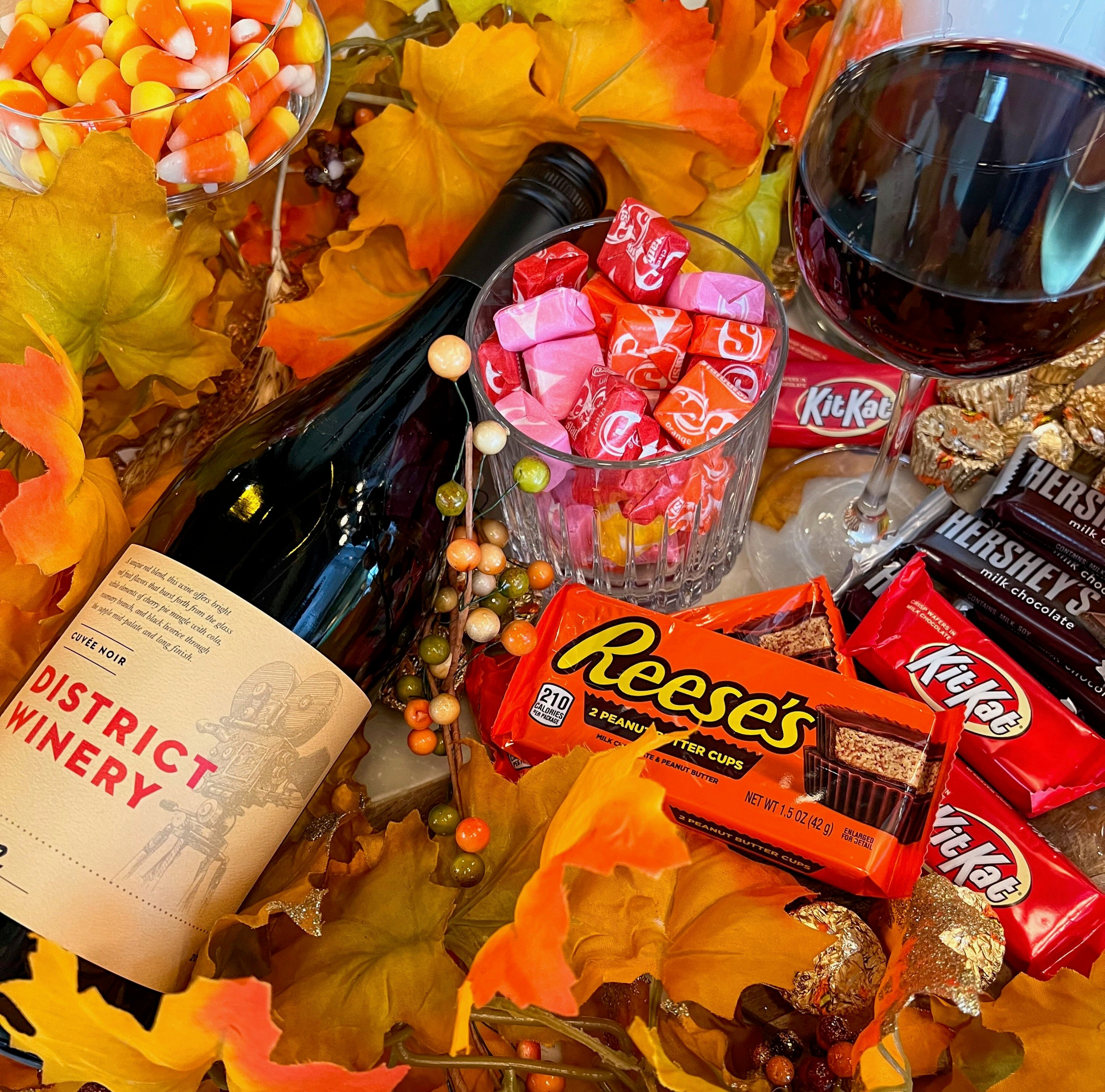 A bottle of wine with the label "District Winery" sits on top of a pile of candy.