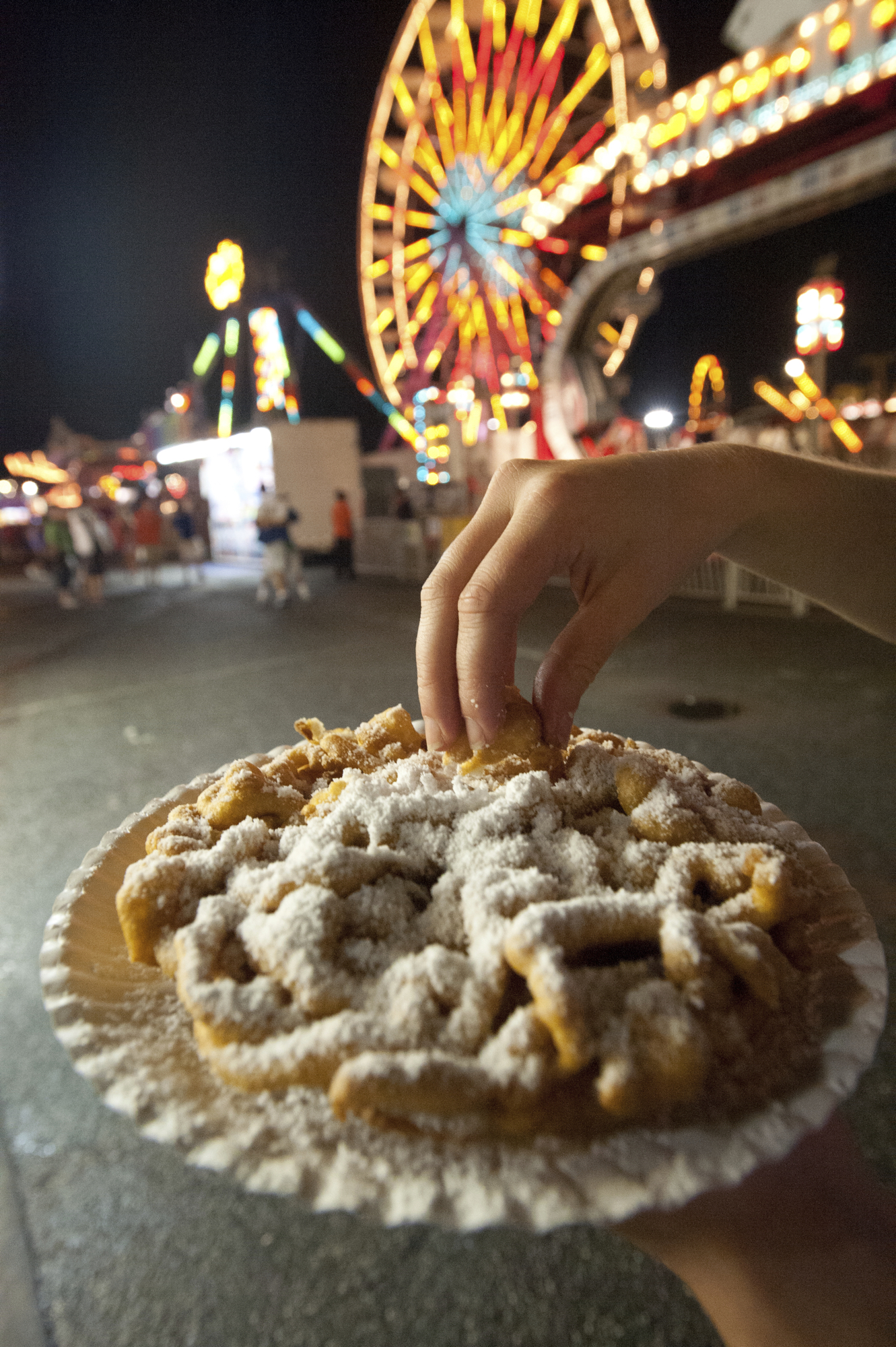 Person eating funnel cake, enjoying the amusement park at the Maryland State Fair, Timonium MD - Washingtonian