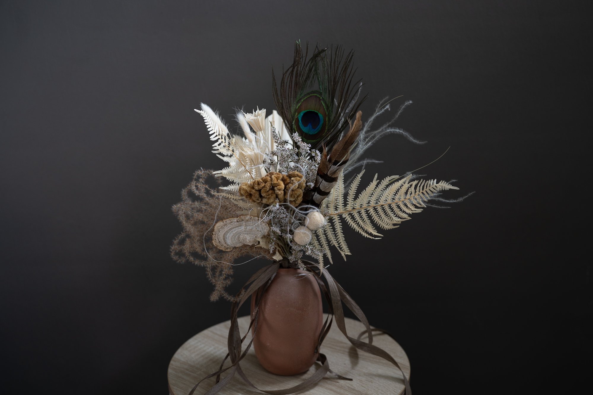An image of preserved flower bouquet featuring a peacock feather.