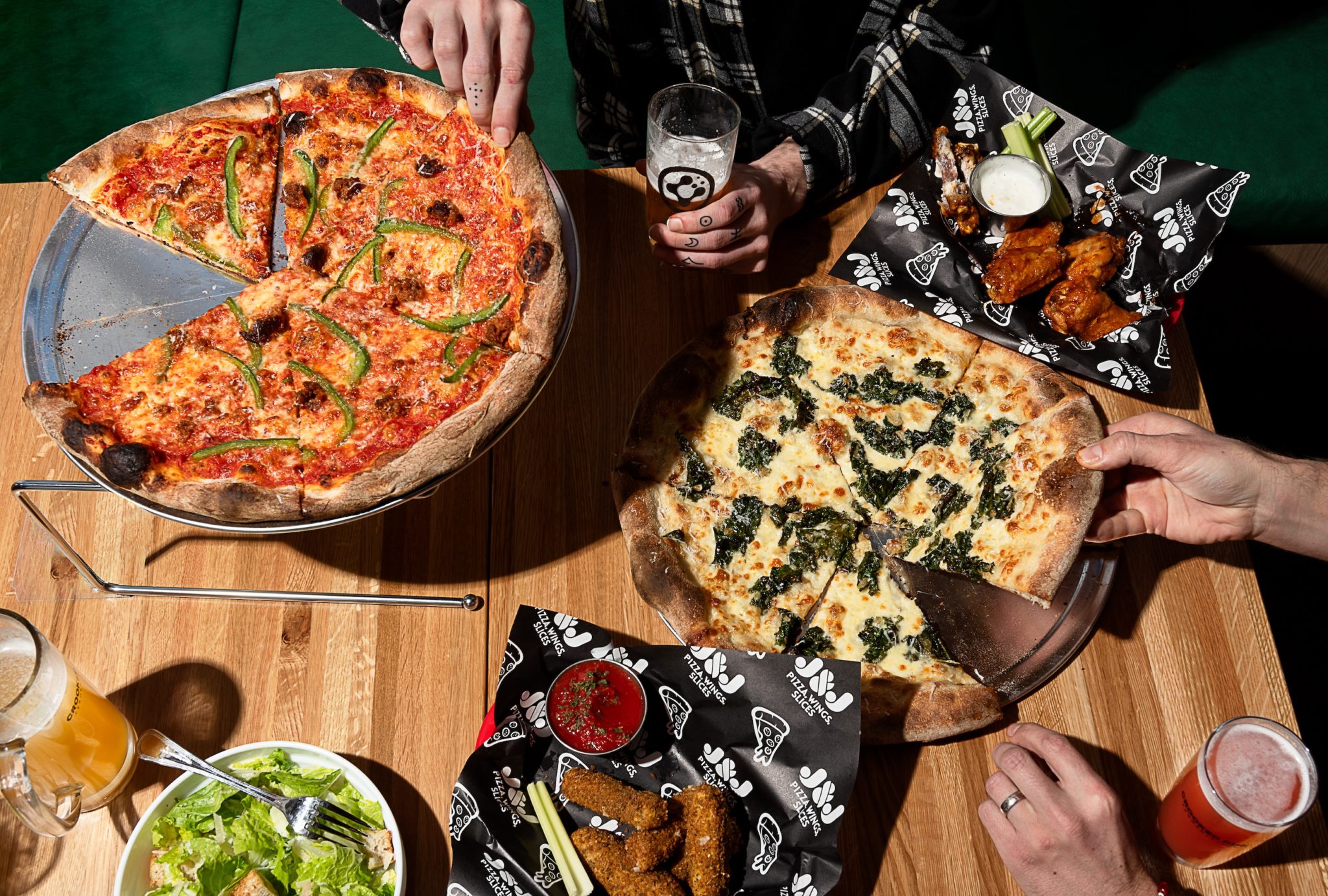 Two pizzas next to a side salad.